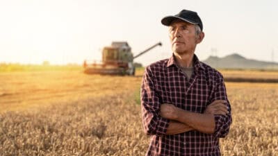 Farmer with arms folded looking ahead.
