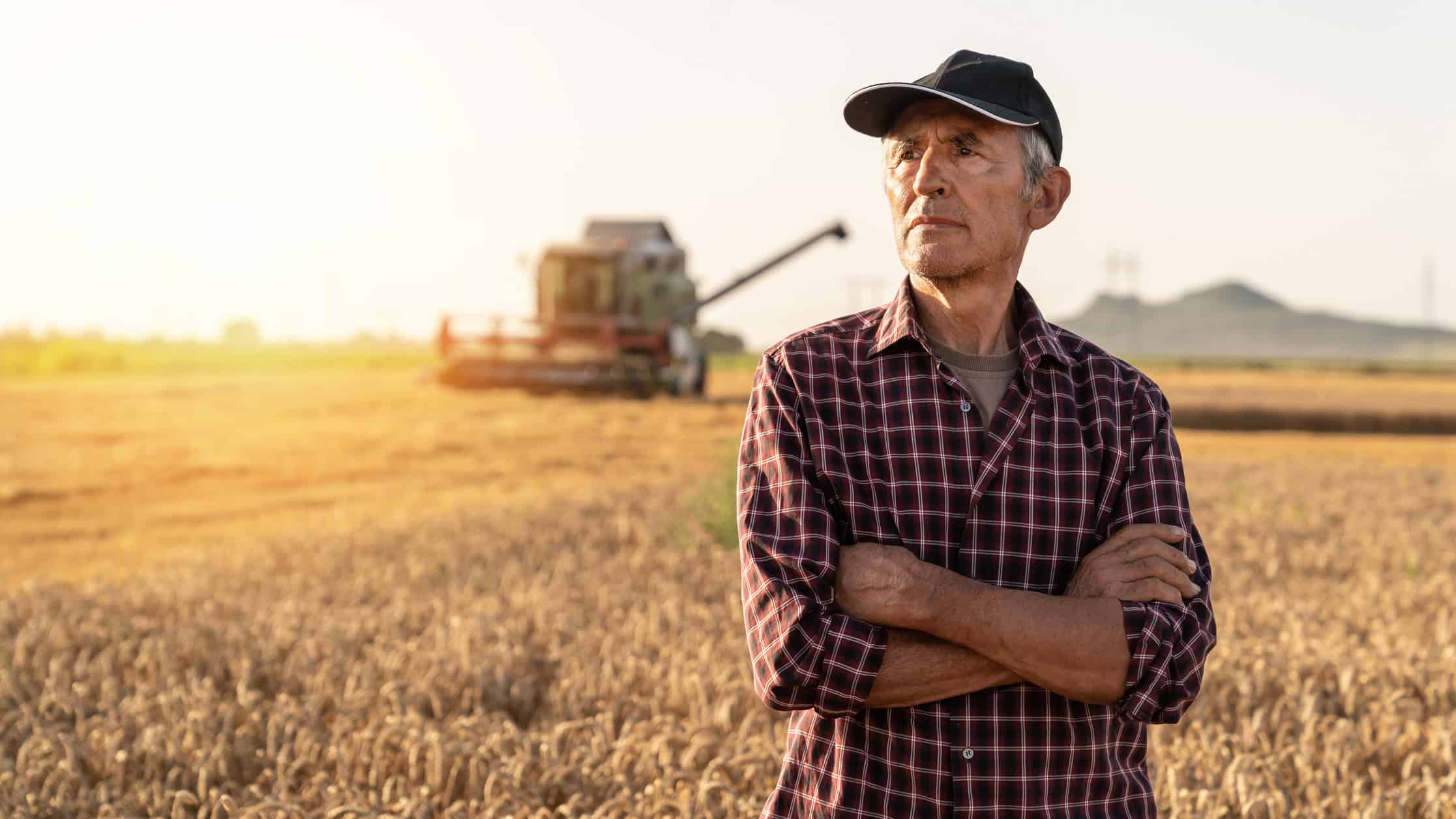 Farmer with arms folded looking ahead.