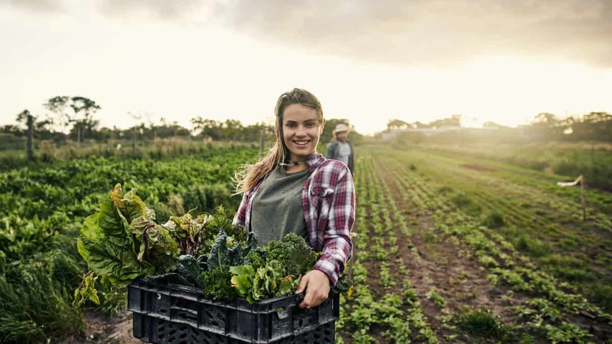Happy female farmer holding fresh produce.