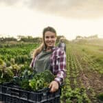 Happy female farmer holding fresh produce.