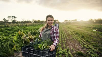 Happy female farmer holding fresh produce.