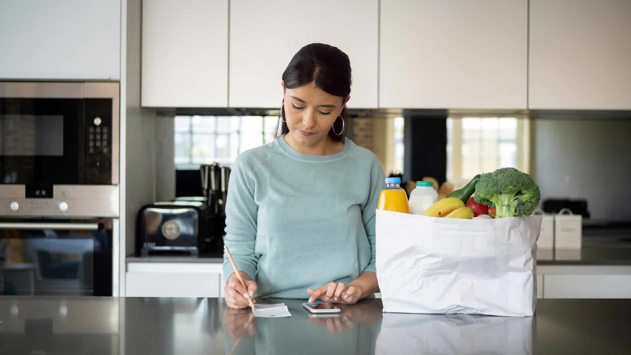 Latin American woman at home checking her budget after grocery shopping.