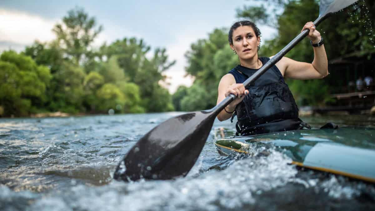 Woman paddling hard in a kayak.