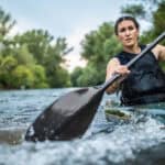Woman paddling hard in a kayak.