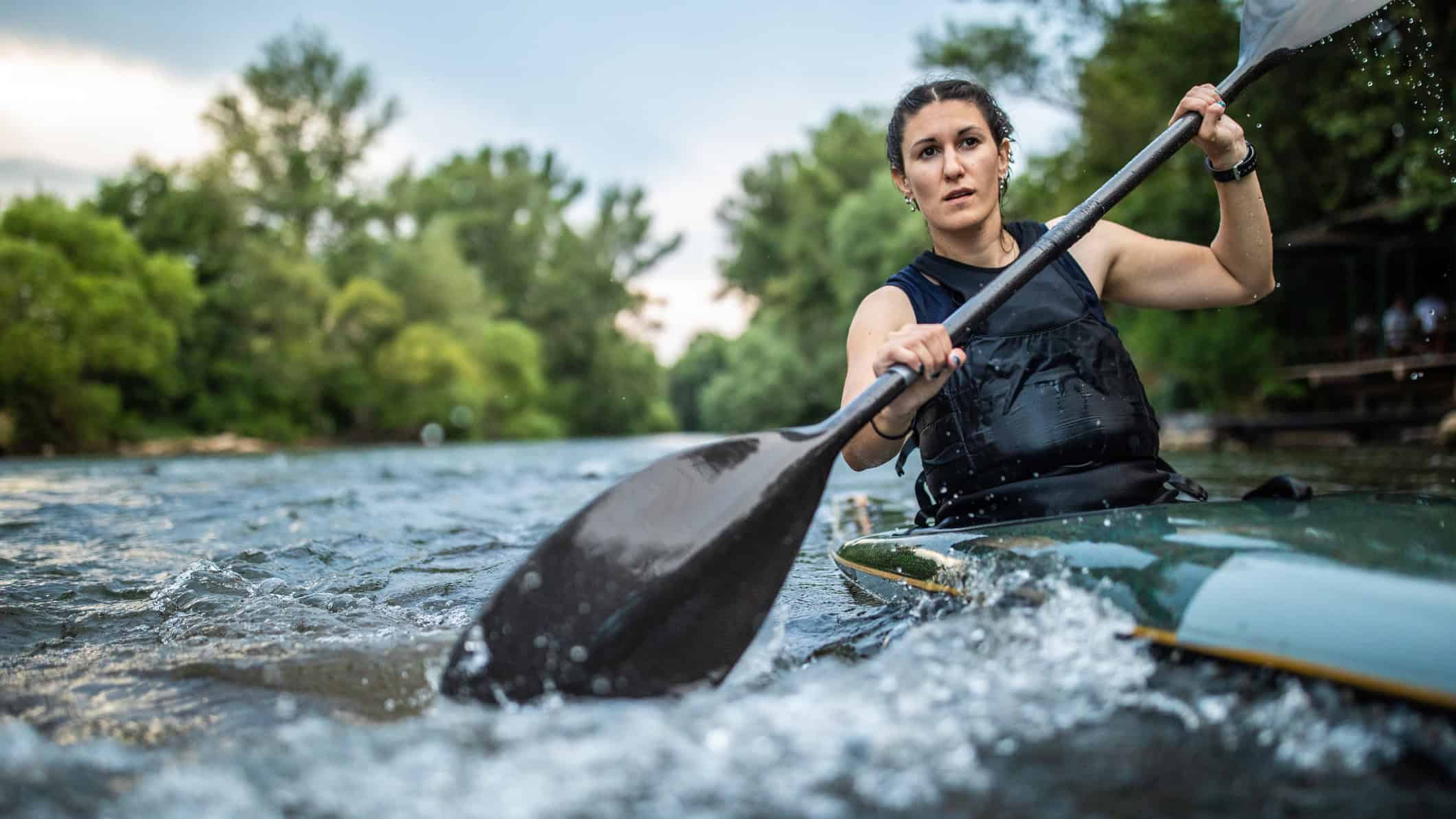 Woman paddling hard in a kayak.