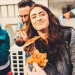 Happy friends at a party enjoying pizza, symbolising the Domino's Pizza share price.