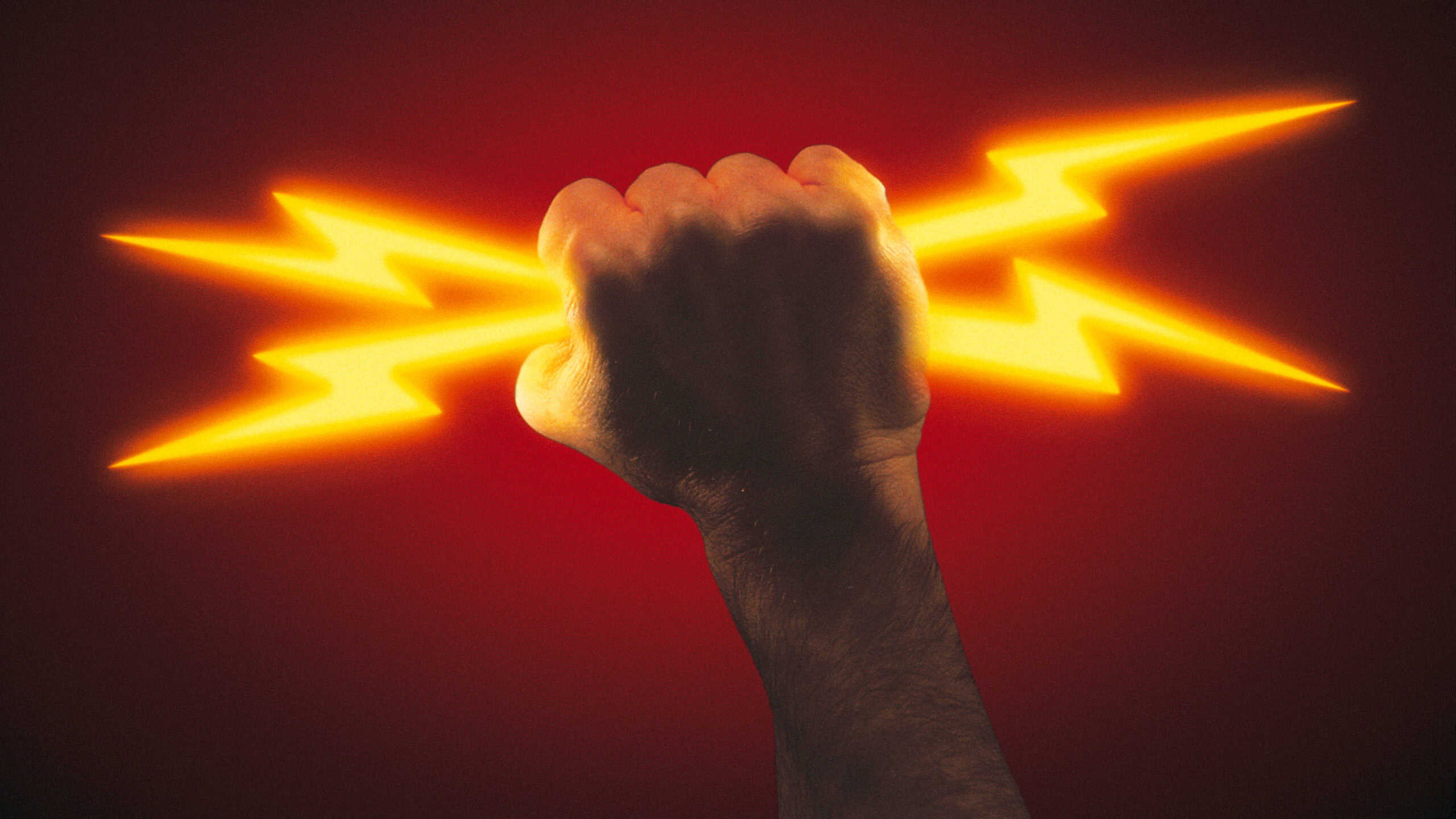 Image of a fist holding two yellow lightning bolts against a red backdrop.