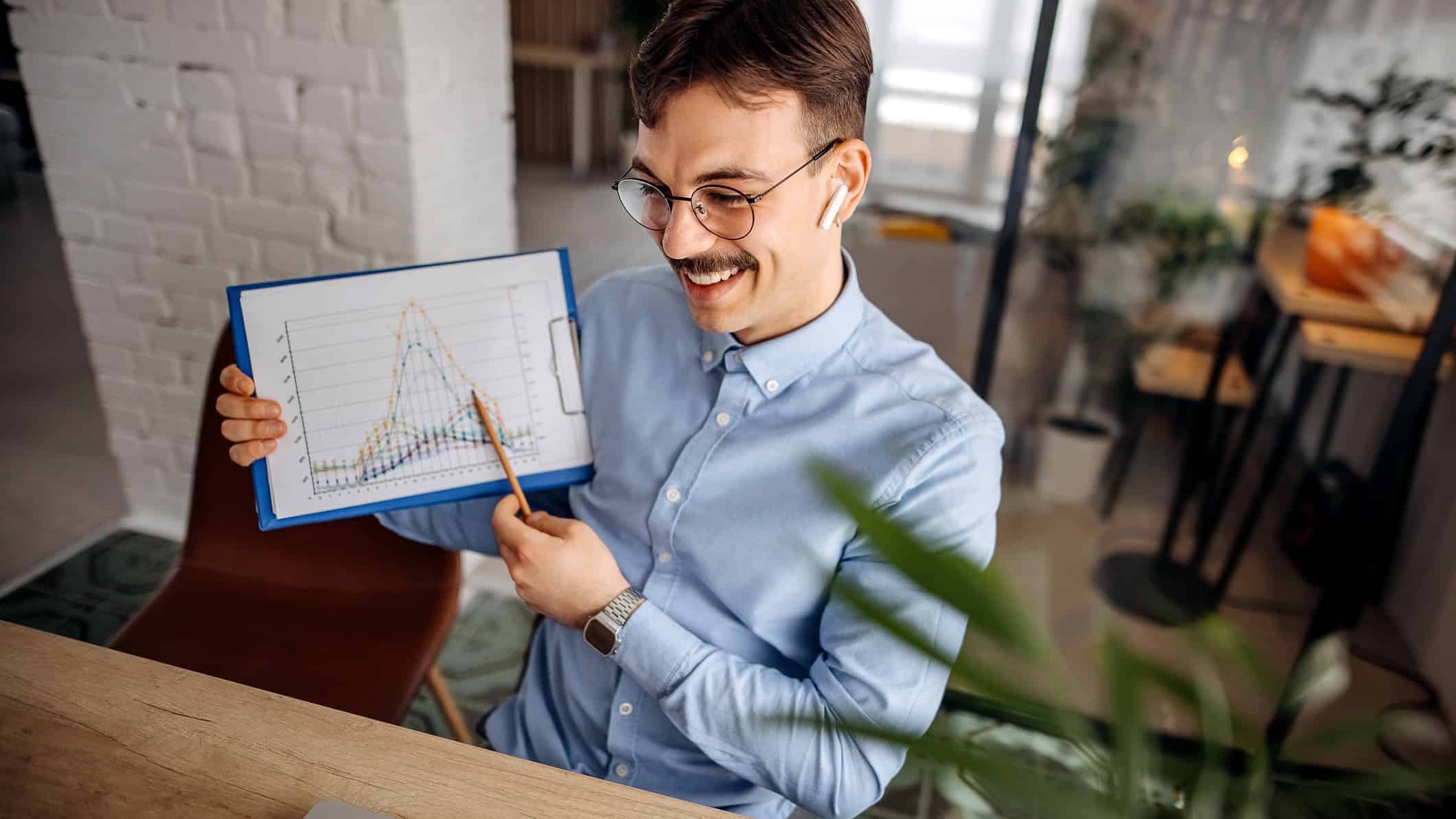 Smiling man points to graph comparing different companies.