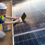 Wlorker on a laptop on top of solar panels.