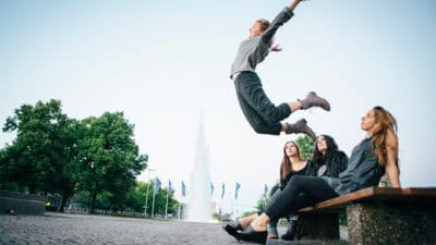 Woman leaping in the air and standing out from her friends who are watching.