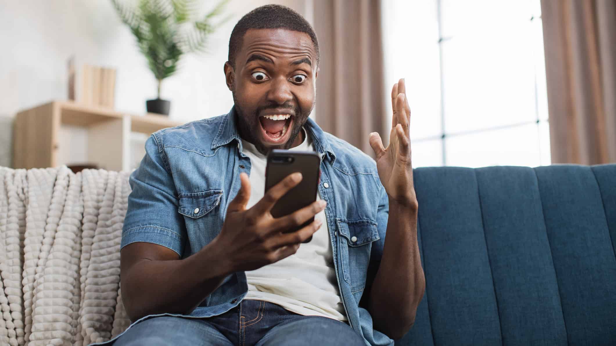Overjoyed man celebrating success with yes gesture after getting some good news on mobile.