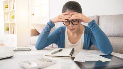 Worried young woman doing banking and administrative work with hands on head.