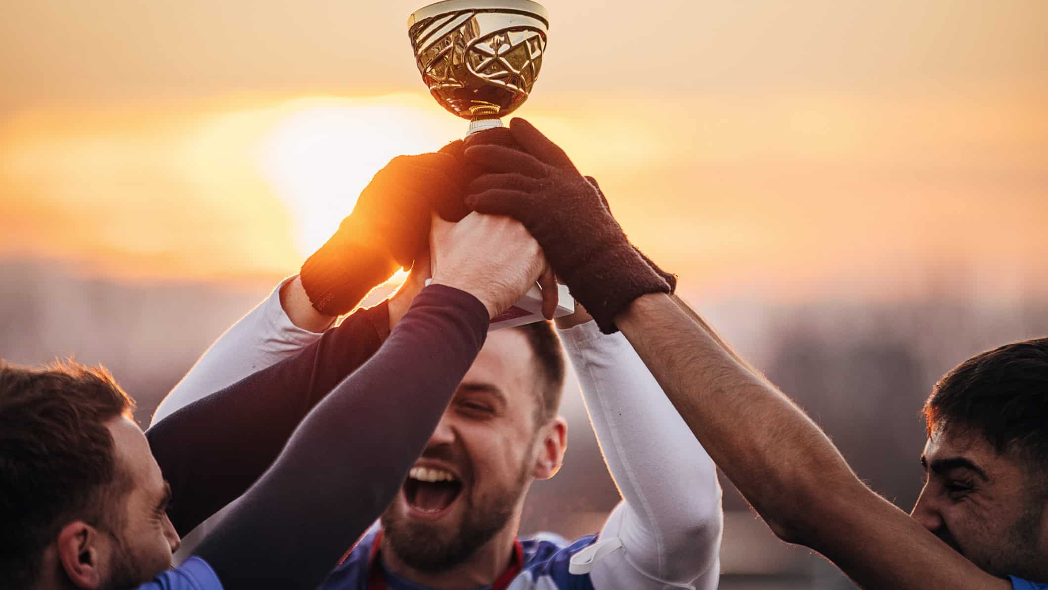 Three happy team mates holding the winners trophy.