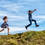 Children skipping and jumping up a hill.