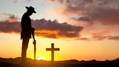 Silhouette of soldier paying tribute against the sunset - stock photo