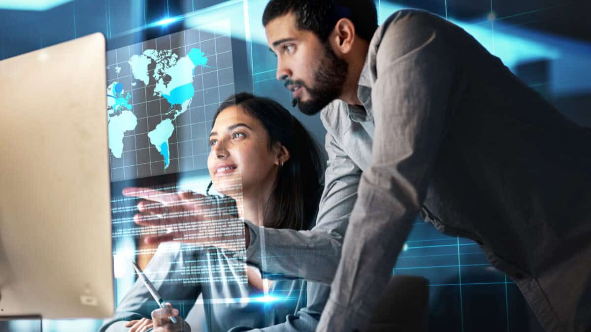 Man working with his colleague with a hologram of a world map.