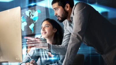 Man working with his colleague with a hologram of a world map.