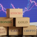 Boxes sitting on a laptop with different asset classes written, amidst a graph background.