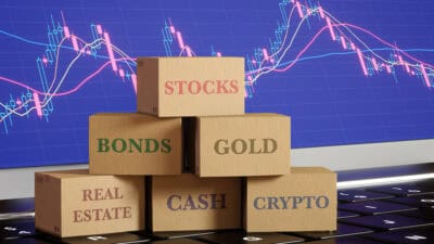 Boxes sitting on a laptop with different asset classes written, amidst a graph background.