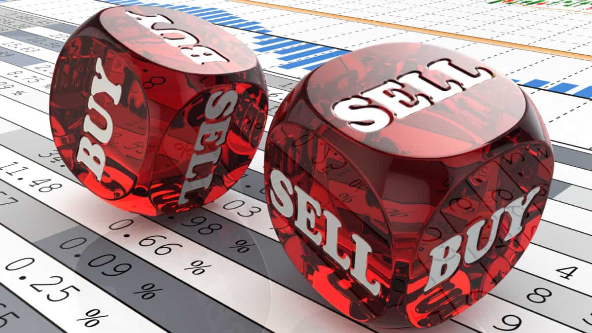 Buy and sell written on red dice on top of stock market charts.