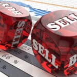 Buy and sell written on red dice on top of stock market charts.