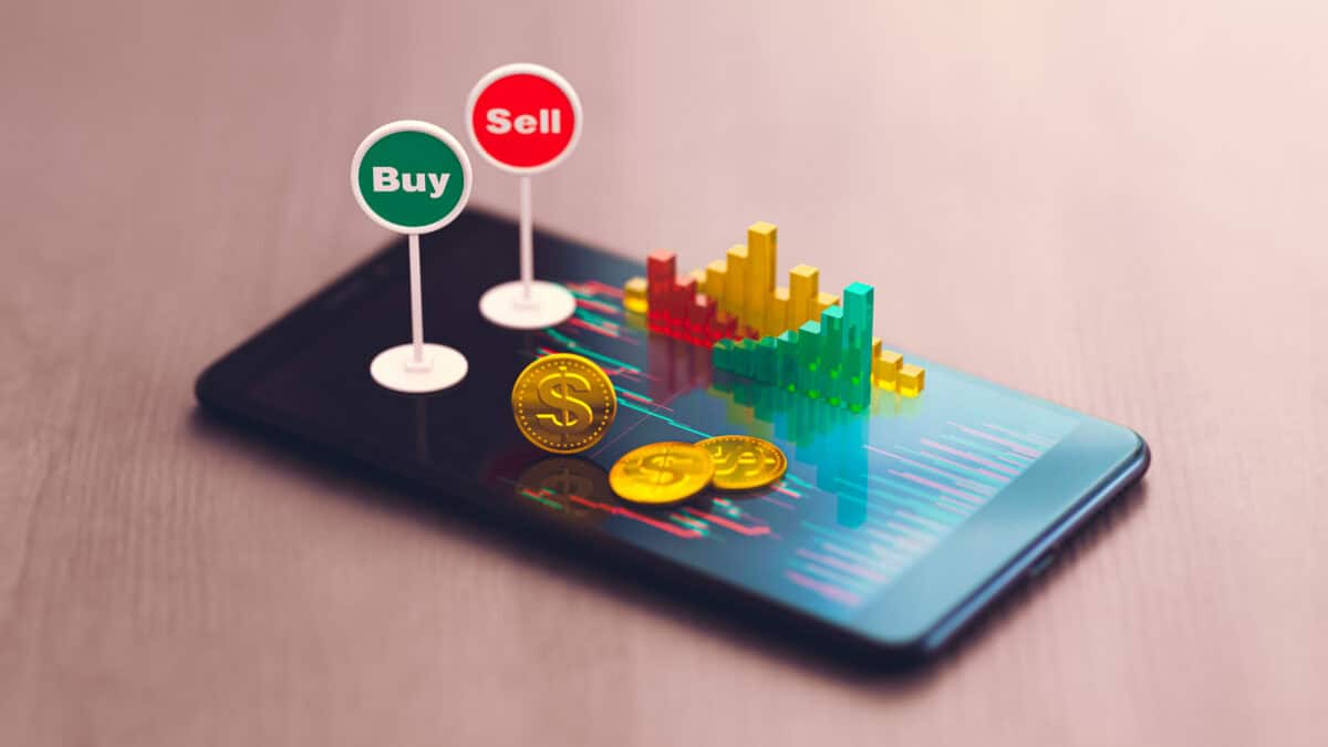 Buy and sell signs on smartphone along with coins and graph models.