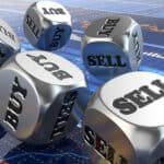 Silver dice with buy and sell written on them on top of stock market charts.