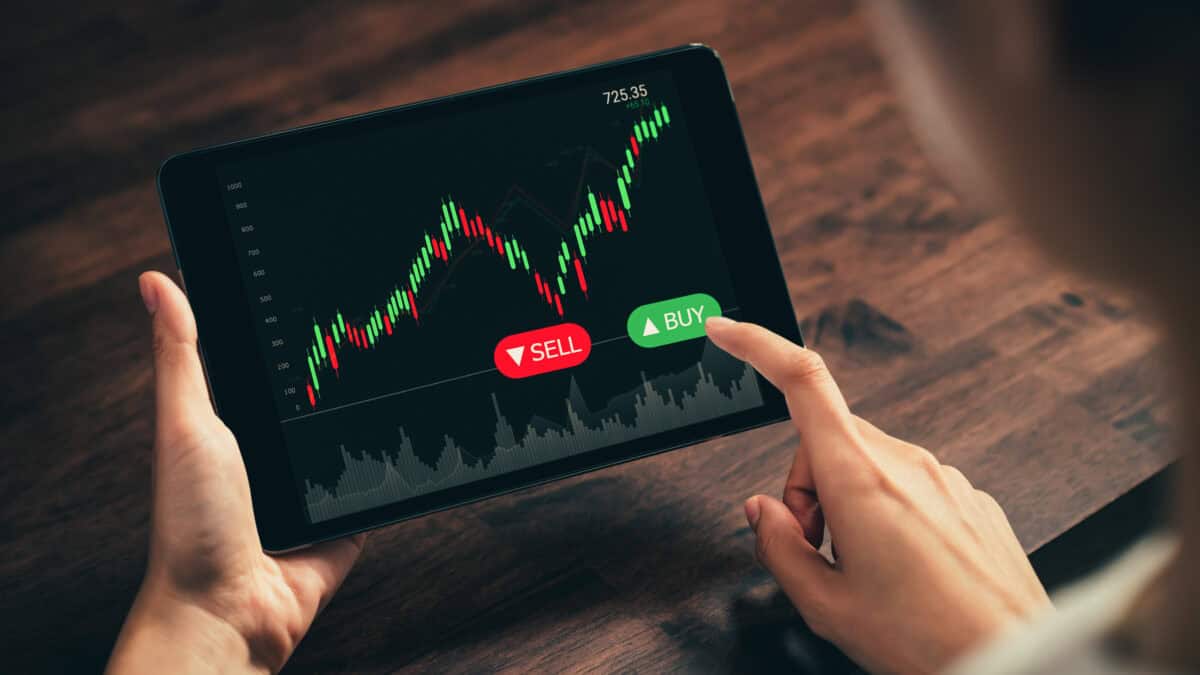 Person on a tablet with buy and sell options for a stock on the screen.
