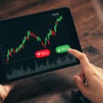 Person on a tablet with buy and sell options for a stock on the screen.