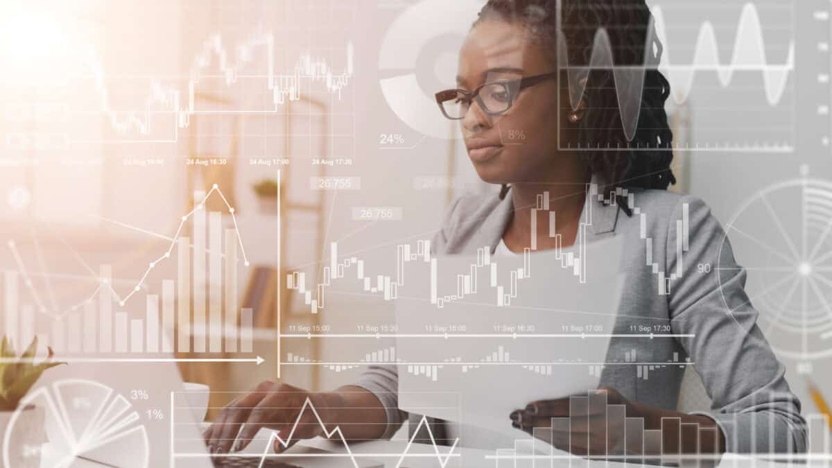 Businesswoman working with laptop and documents in office, with virtual finance related graphs and charts.