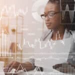 Businesswoman working with laptop and documents in office, with virtual finance related graphs and charts.