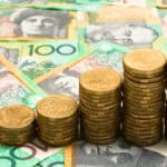 Piles of increasing coins on Australian $100 notes.