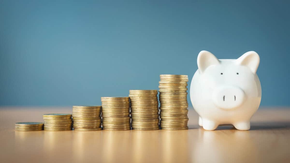 Rising stacks of coins next to a piggy bank.