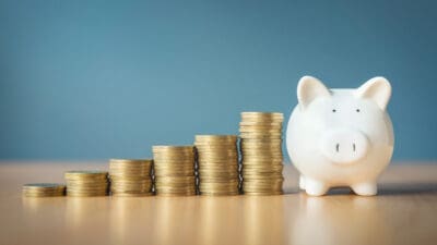 Rising stacks of coins next to a piggy bank.