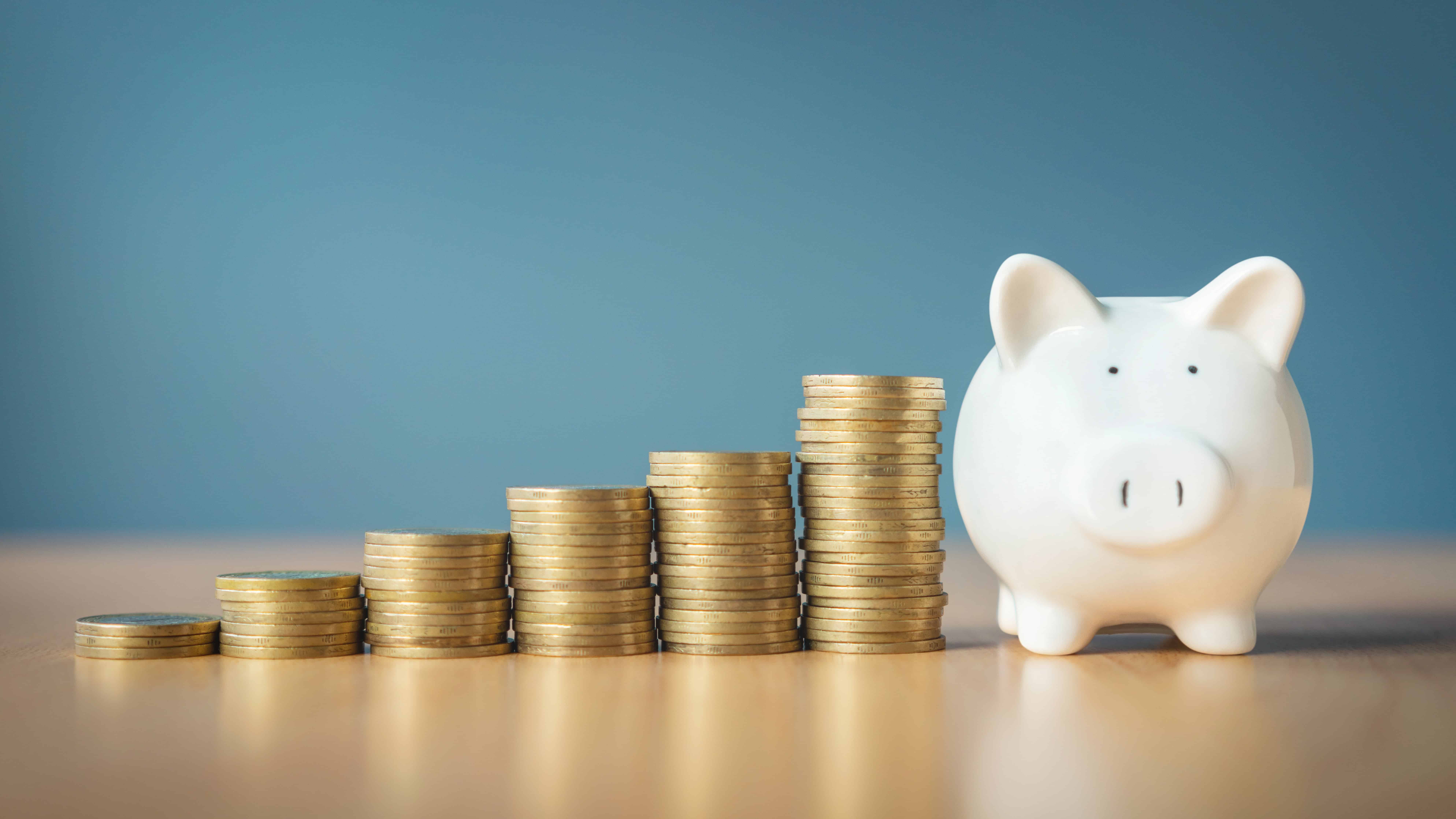 Rising stacks of coins next to a piggy bank.