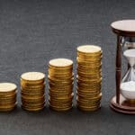 Piles of increasing coins alongside an hourglass.