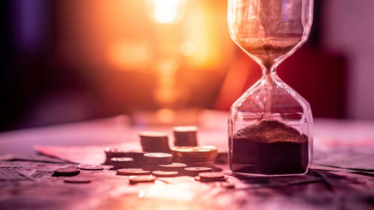 Hour glass next to pile of coins and notes.