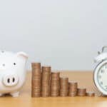 Coins in ascending order from left to right, with a piggy bank and clock on the sides.
