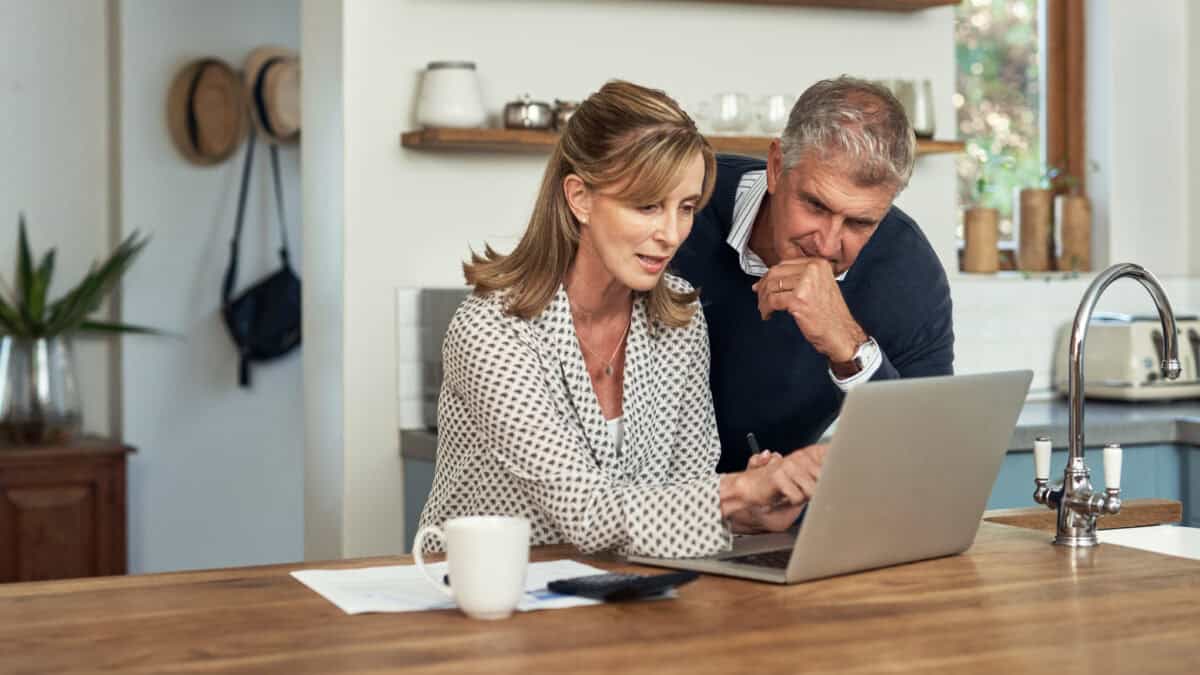 Mid-aged couple looking at a laptop.