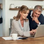 Mid-aged couple looking at a laptop.