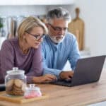 Couple on their laptop in their home kitchen.