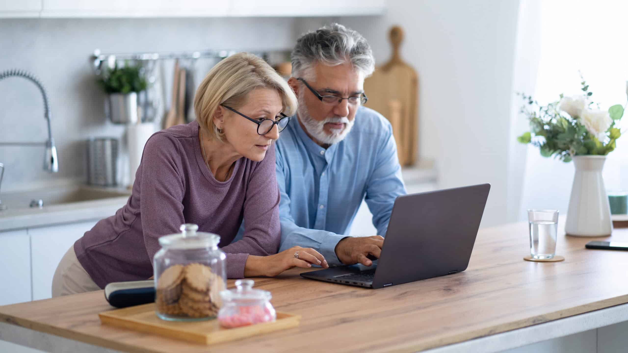Couple on their laptop in their home kitchen.