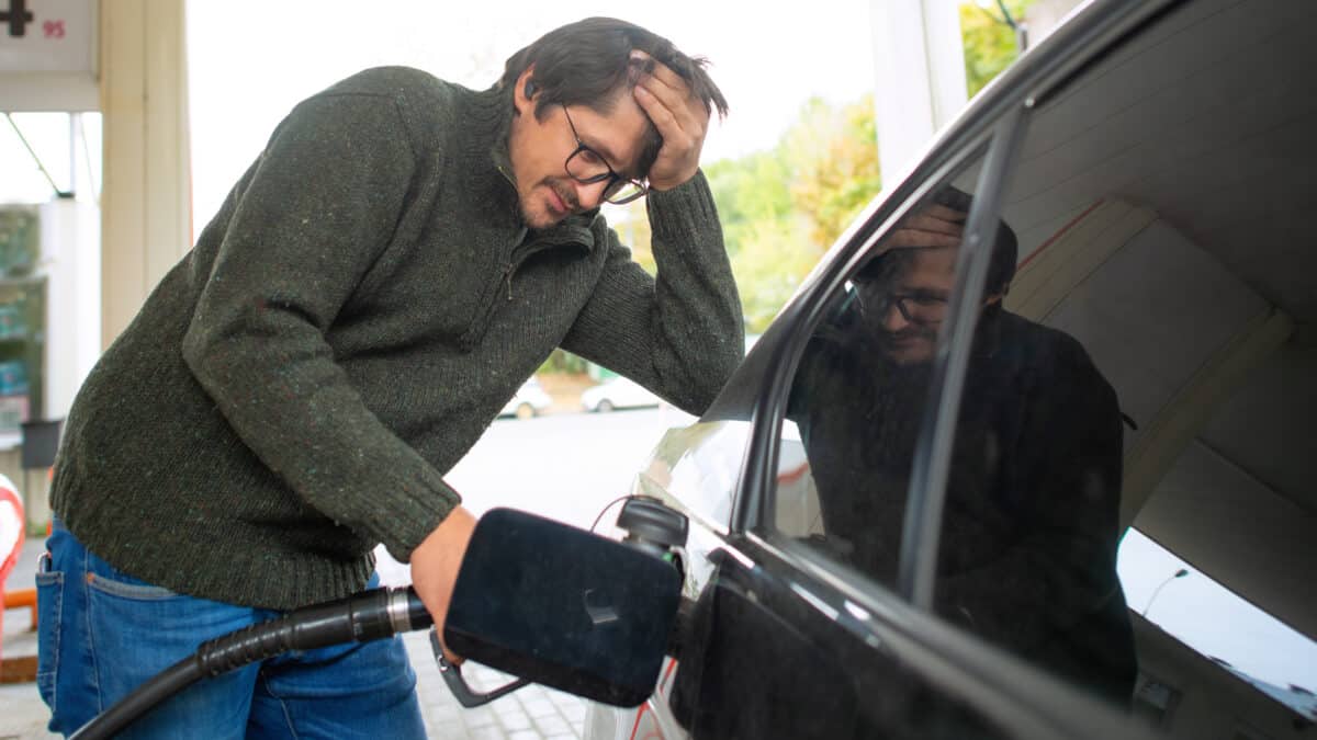 Devastated man putting petrol in his car.