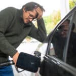 Devastated man putting petrol in his car.