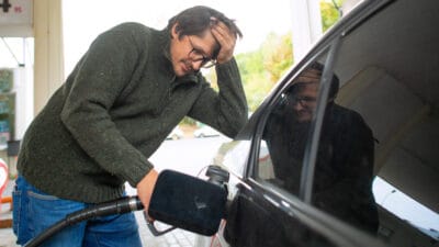 Devastated man putting petrol in his car.