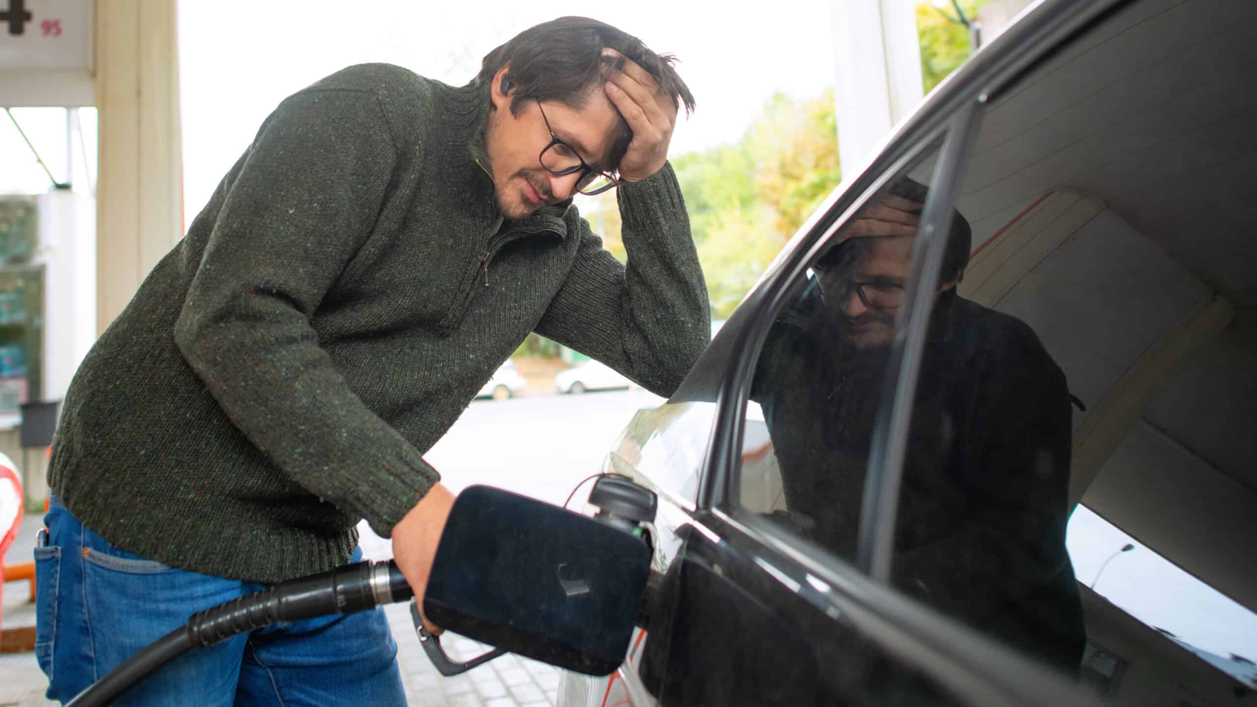 Devastated man putting petrol in his car.