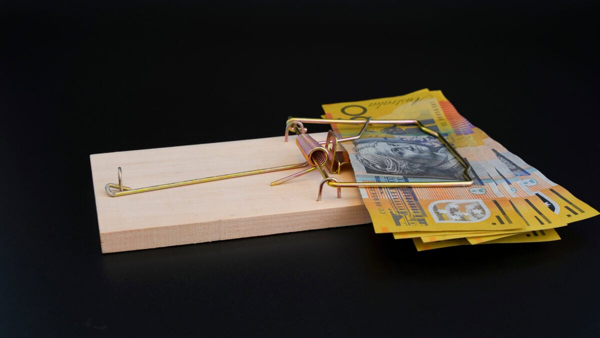 Rat trap with Australian $50 notes on black background.