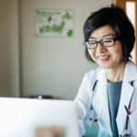 Happy doctor using her laptop.
