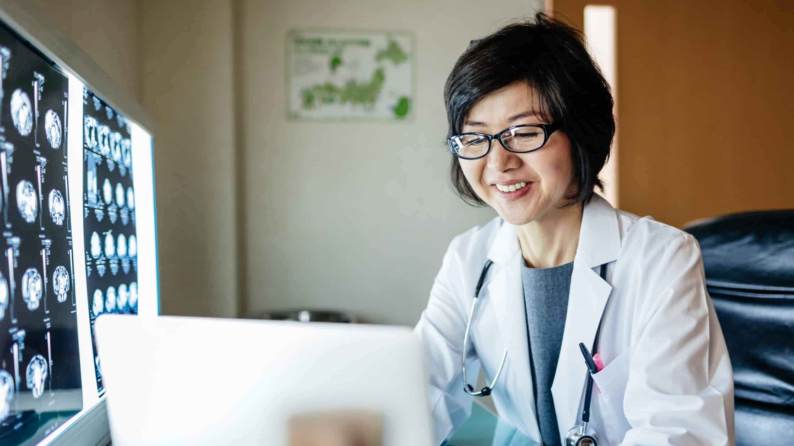 Happy doctor using her laptop.