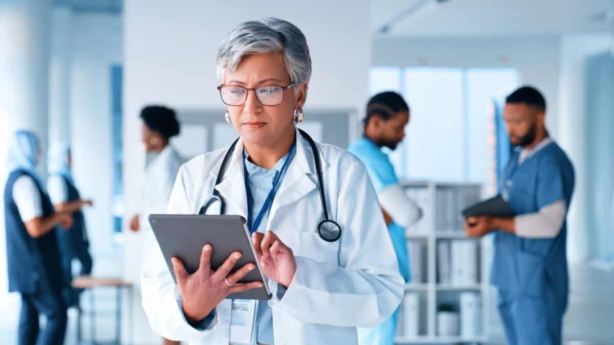 Doctor with stethoscope using a tablet in a hospital.